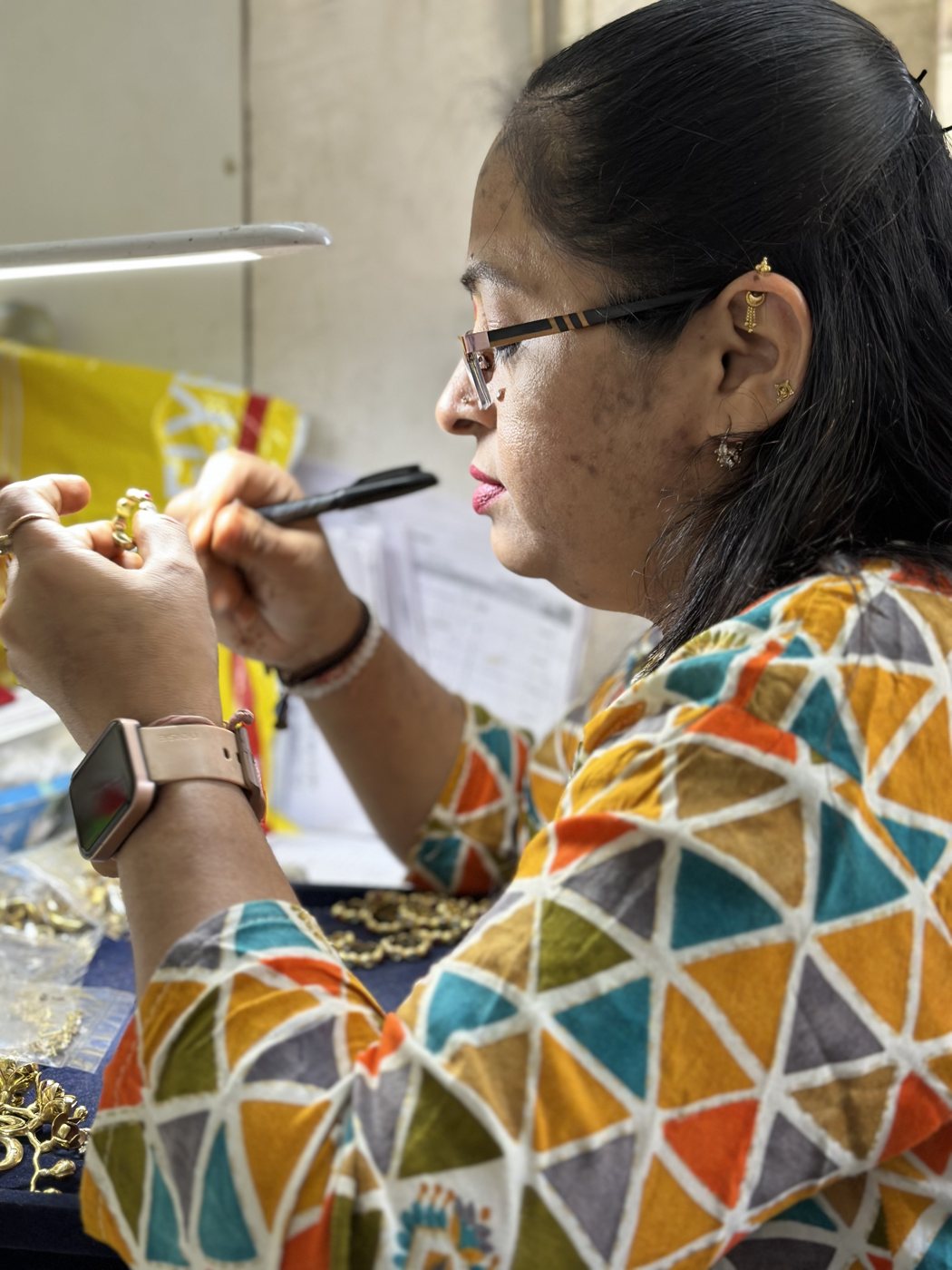 Woman artisan detailing gold jewelry findings at her bench in the DVNJEWELRY atelier